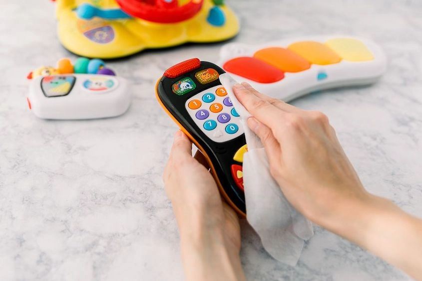 Đồ chơi và bình sữa được lau bằng khăn giấy ướt, cảnh báo rủi ro cho hệ tiêu hóa trẻ.